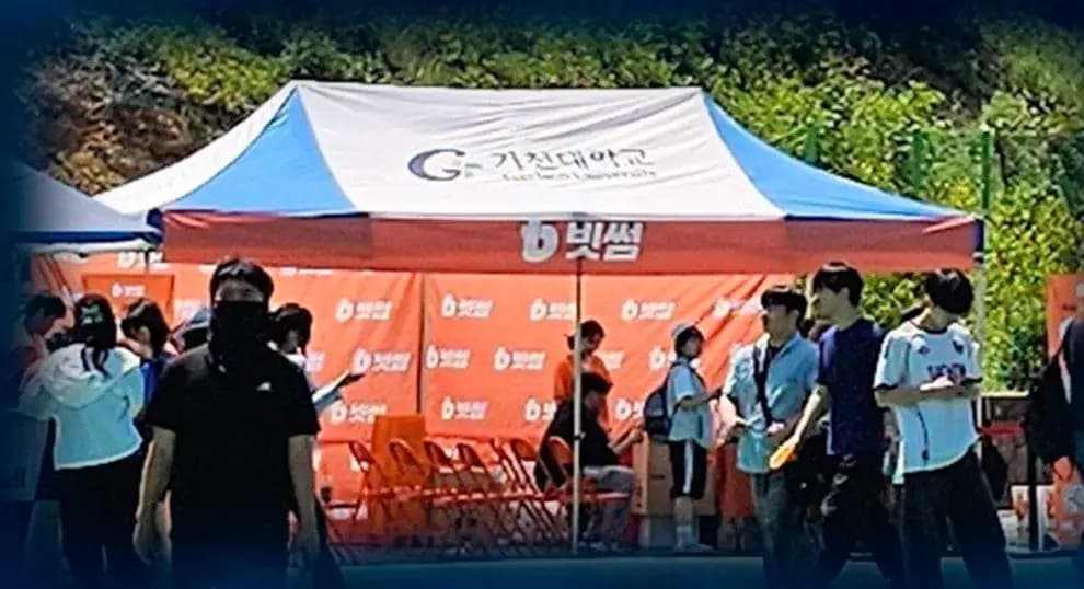 가천대학교 캠퍼스 야외에서 운영된 브랜드 스폰서십 부스. 오렌지·화이트 캐노피 텐트와 방문 학생이 보인다.